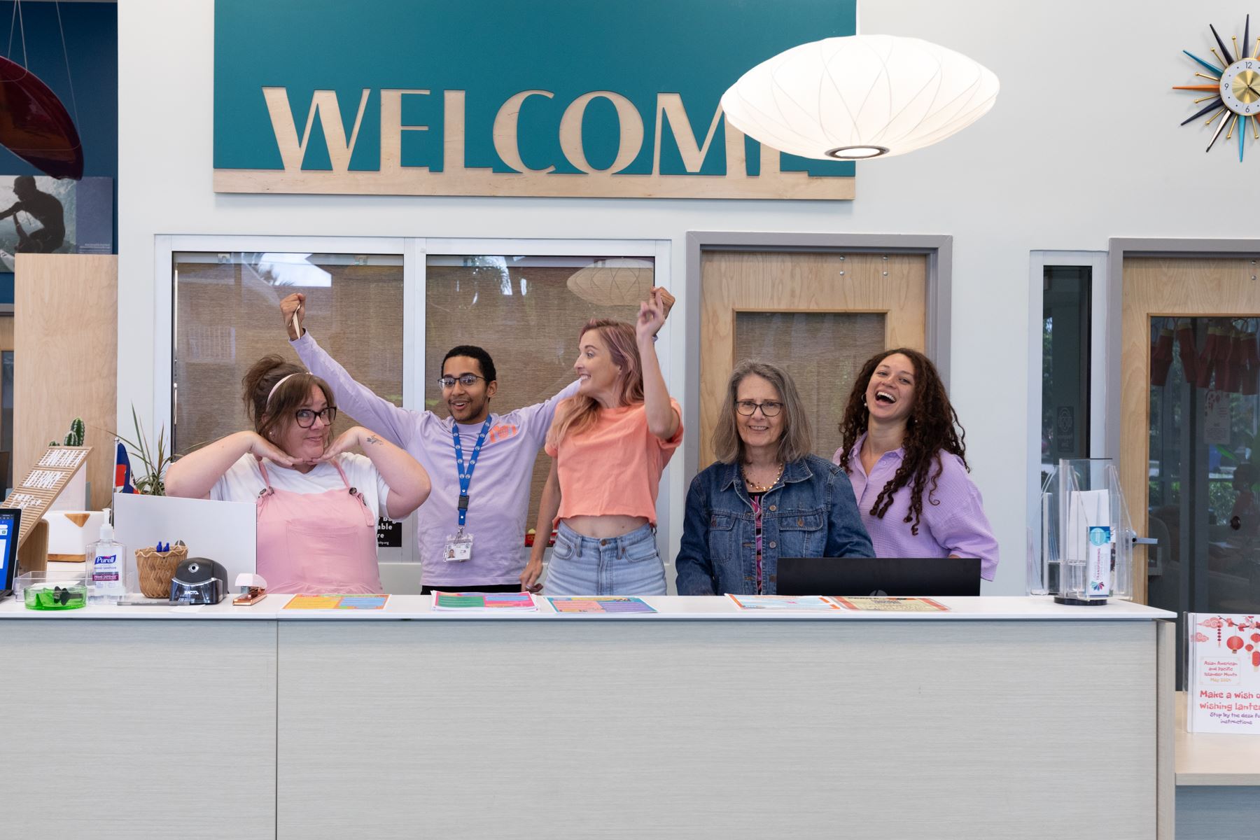 5 library staff members jumping and making silly faces under welcome sign